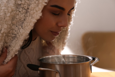 picture of a lady smell the steam from a pot
