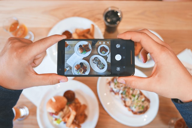 person taking picture of food on plates