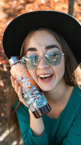 smiling woman holding a bottle of boba tea to her face