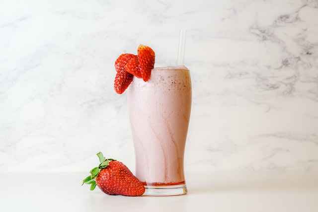 strawberry vanilla shake in clear glass with strawberry fruits