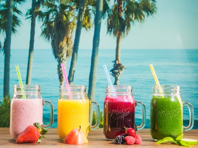 variety of fruit drinks in mason jars with the beach as the background